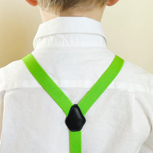 The back of a child wearing a white dress shirt and hot lime green suspenders