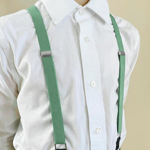 A boy wearing seafoam suspenders with a white dress shirt