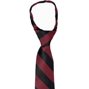The knot and collar on a boys' burgundy and black striped zipper tie