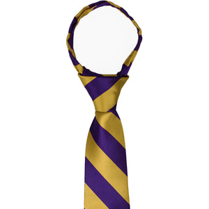 The collar and knot on a boys pre-tied dark purple and gold zipper tie