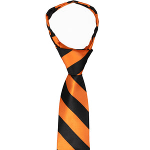 The collar and pre-tied knot on a boys' orange and black striped zipper tie