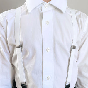 Boy wearing a pair of white suspenders over a white dress shirt