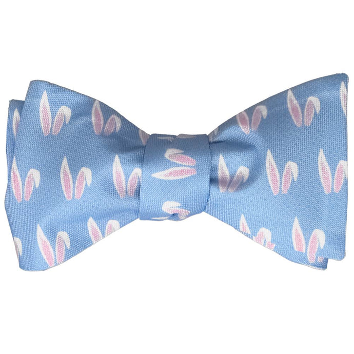 A self-tie bow tie, tied, with an all over bunny ears pattern on a blue background