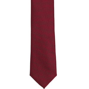The front of a burgundy textured skinny tie, laid out flat