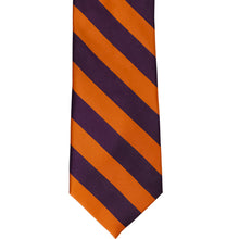 Load image into Gallery viewer, The front of a burnt orange and eggplant purple striped tie, laid out flat