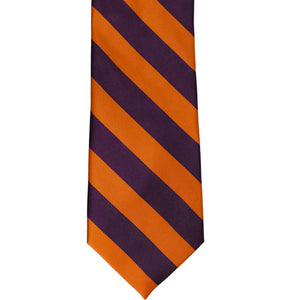The front of a burnt orange and eggplant purple striped tie, laid out flat
