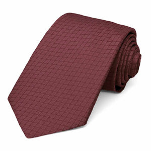 A dark red lattice patterned necktie, rolled to show the subtle texture