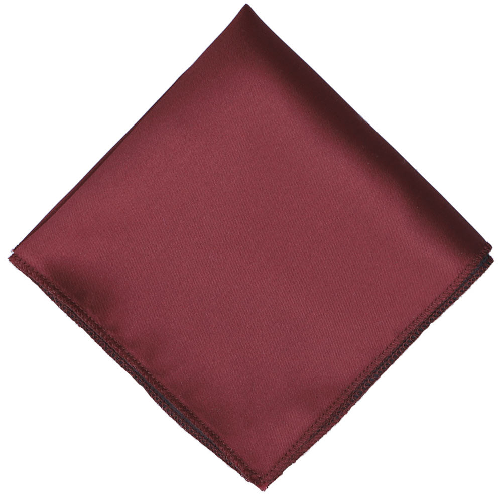 A solid pinot colored pocket square folded to a diamond