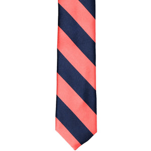 The front of a bright coral and navy blue striped skinny tie, laid out flat