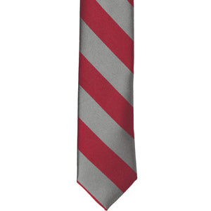 The front of a crimson red and gray striped skinny tie, laid out flat