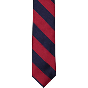 The front of a crimson red and navy blue striped skinny tie, laid out flat