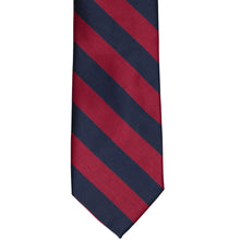 Load image into Gallery viewer, The front of a crimson red and navy blue striped tie, laid out flat
