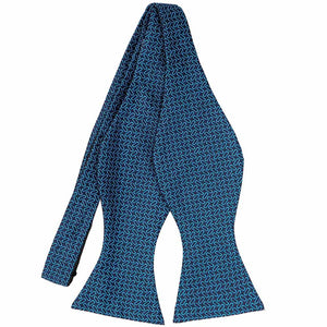 A navy blue self-tie bow tie, untied, with a bright blue small oval pattern