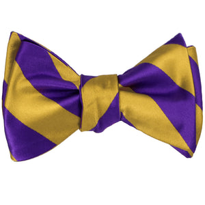 A dark purple and gold striped self-tie bow tie, tied