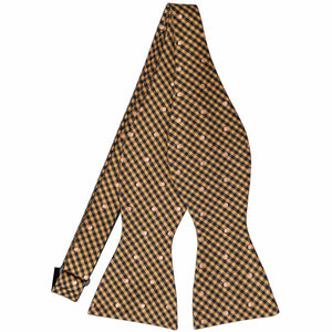 An untied self-tie bow tie in a gold bar and black gingham pattern