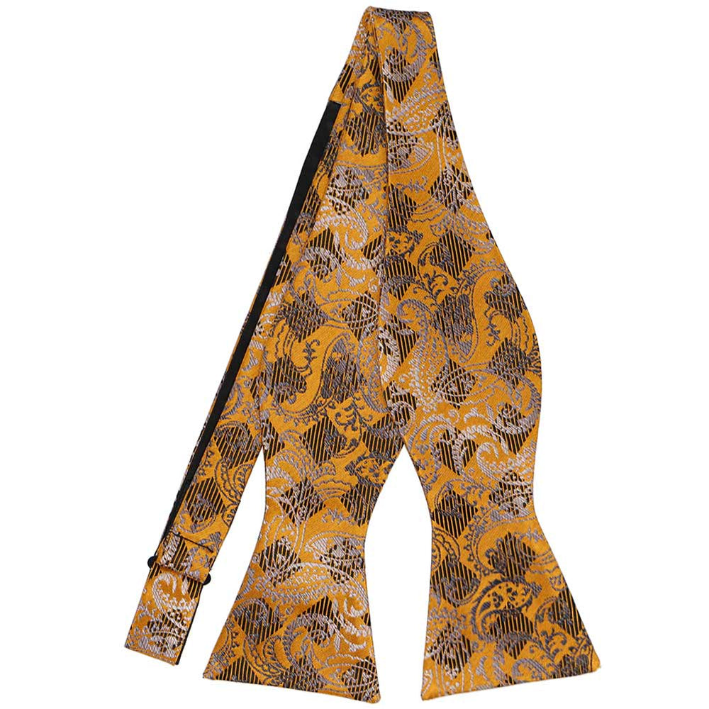 An untied paisley bow tie in shades of gold bar, black and silver