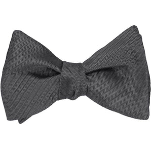 A tied graphite gray self-tie bow tie in a herringbone pattern