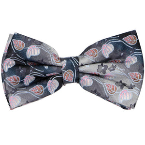 A pre-tied bow tie with a flower and leaf pattern on a gray and silver gradient background