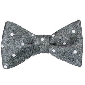 A tied gray textured bow tie with white polka dots