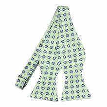 Load image into Gallery viewer, An untied light green self-tie bow tie with small blue medallions