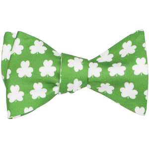 A green self-tie bow tie, tied, with white clovers in an all over pattern
