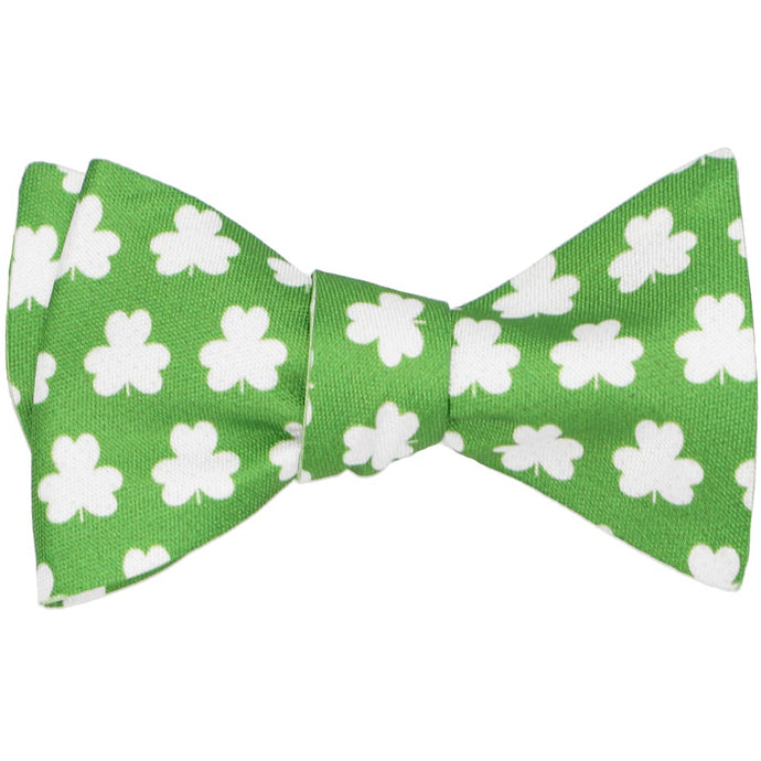 A green self-tie bow tie, tied, with white clovers in an all over pattern