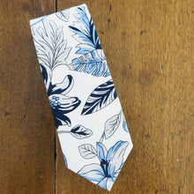 Load image into Gallery viewer, A blue and white Hawaiian floral tie on a wood background