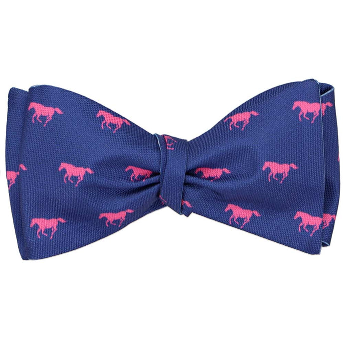 A tied self-tie bow tie with hot pink horses on a dark blue background