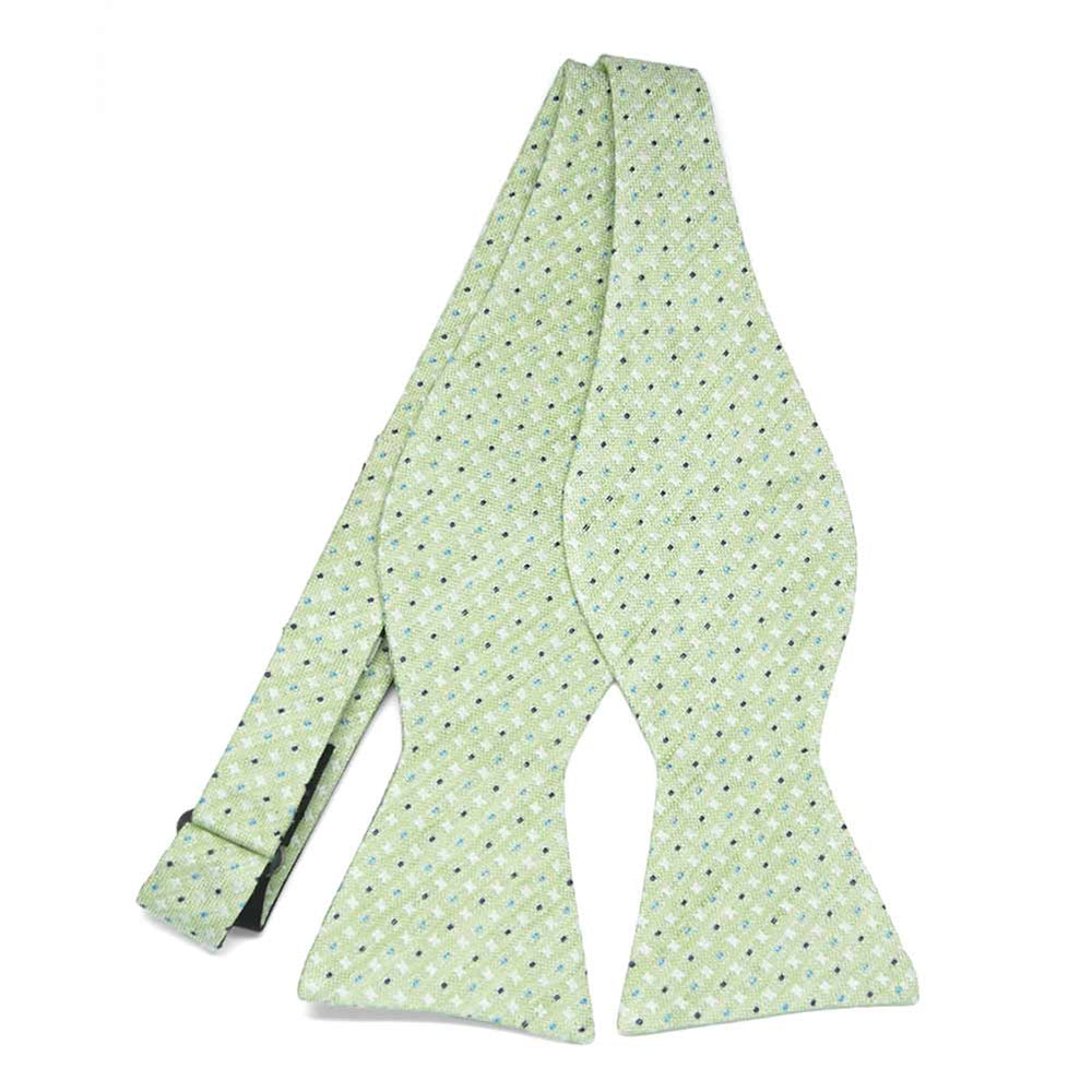 An untied light green self-tie bow tie with a small white light blue and dark blue check pattern