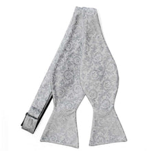 Load image into Gallery viewer, An untied silver self-tie bow tie with a silver floral pattern