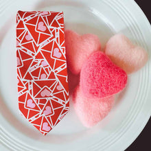 Load image into Gallery viewer, A folded necktie with Valentine letters on it, displayed on a white plate with small wool hearts