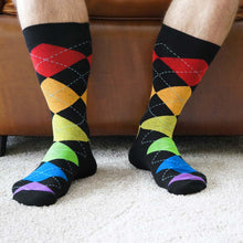 Load image into Gallery viewer, Man sitting in leather chair wearing rainbow argyle socks