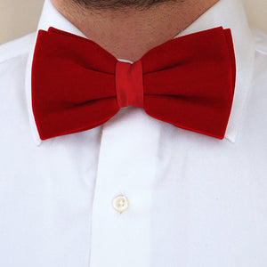 Closeup of a man wearing a red velvet bow tie with a white dress shirt  Edit alt text