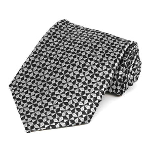 A black and gray geometric pattern necktie, rolled to show details up close