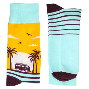 A pair of folded men's novelty socks with a sunset beach scene
