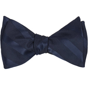 A navy blue self-tie bow tie, tied, in tone-on-tone stripes