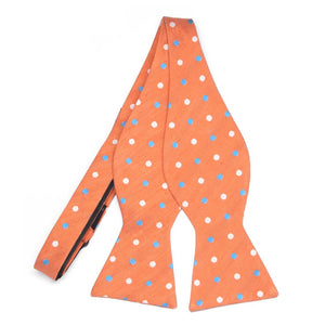 An untied orange self-tie bow tie with white and blue dots
