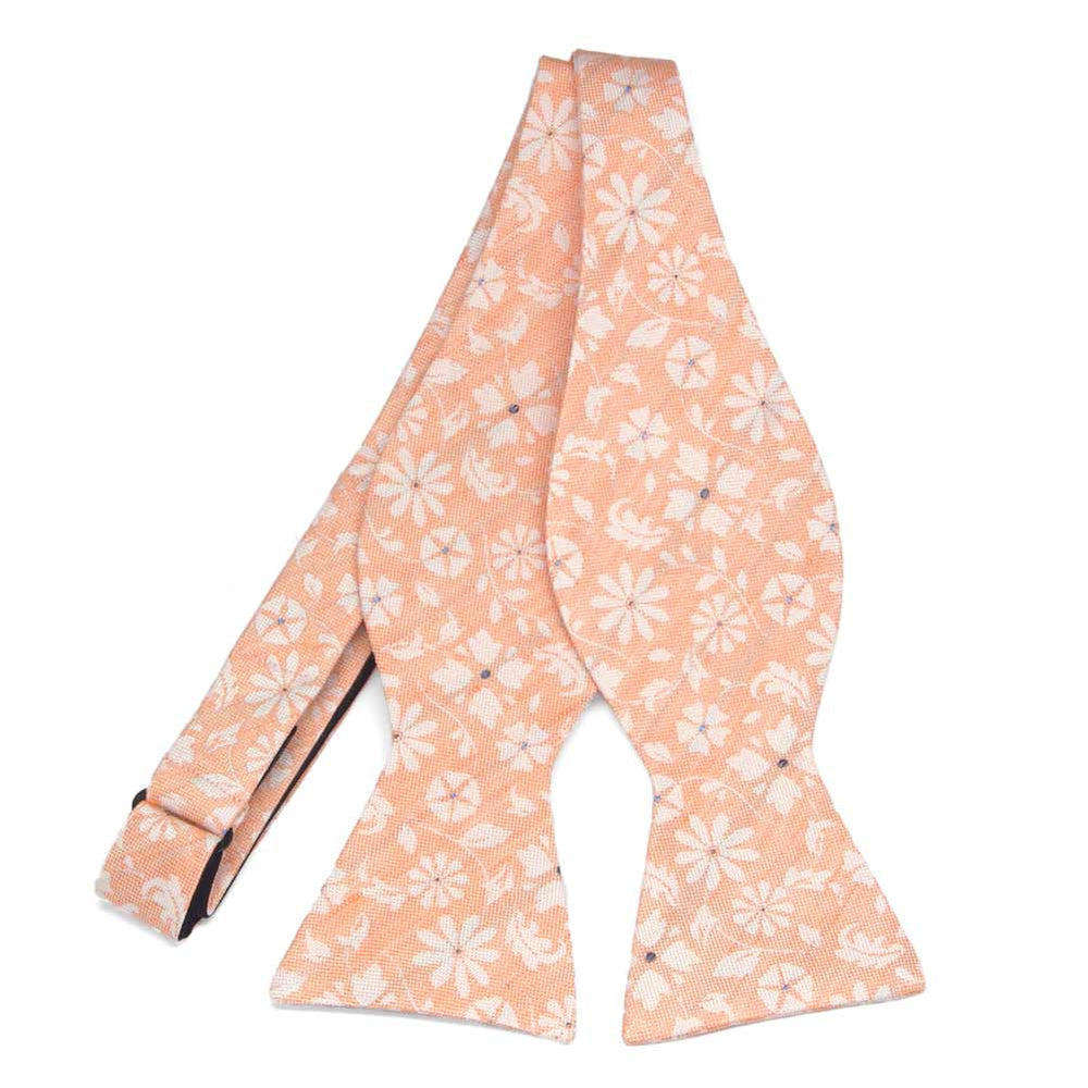 An untied peach self-tie bow tie with white flowers