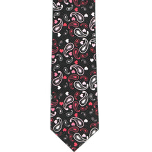 Load image into Gallery viewer, The front, flat view of a black slim tie with a red and pink paisley pattern