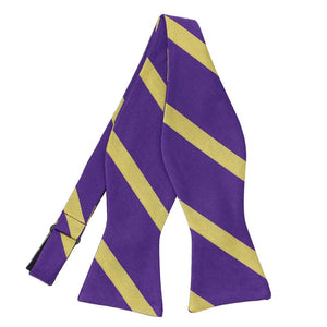 An untied self-tie bow tie in purple and gold stripes