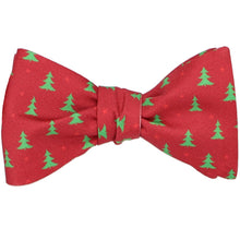 Load image into Gallery viewer, A tied red self-tie bow tie with a smaller green Christmas tree scattered pattern