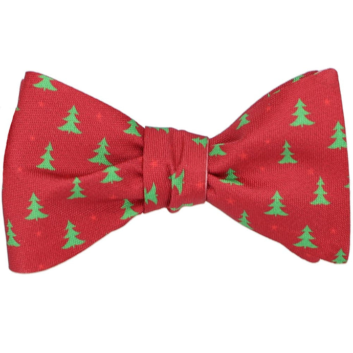 A tied red self-tie bow tie with a smaller green Christmas tree scattered pattern