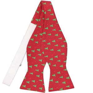 An untied self-tie bow tie in a red and green small Christmas tree pattern