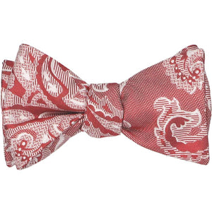 A tied self-tie bow tie in a red and white paisley pattern with some texture