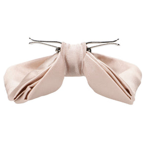 An opened sand pink clip-on bow tie, side view