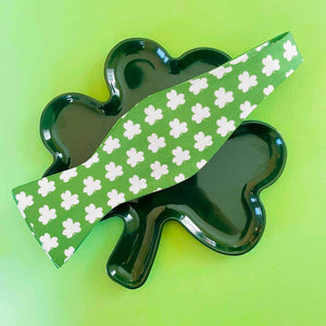 A green bow tie with white shamrocks on a shamrock plate