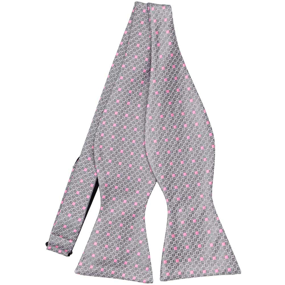 An untied silver bow tie with pink polka dots