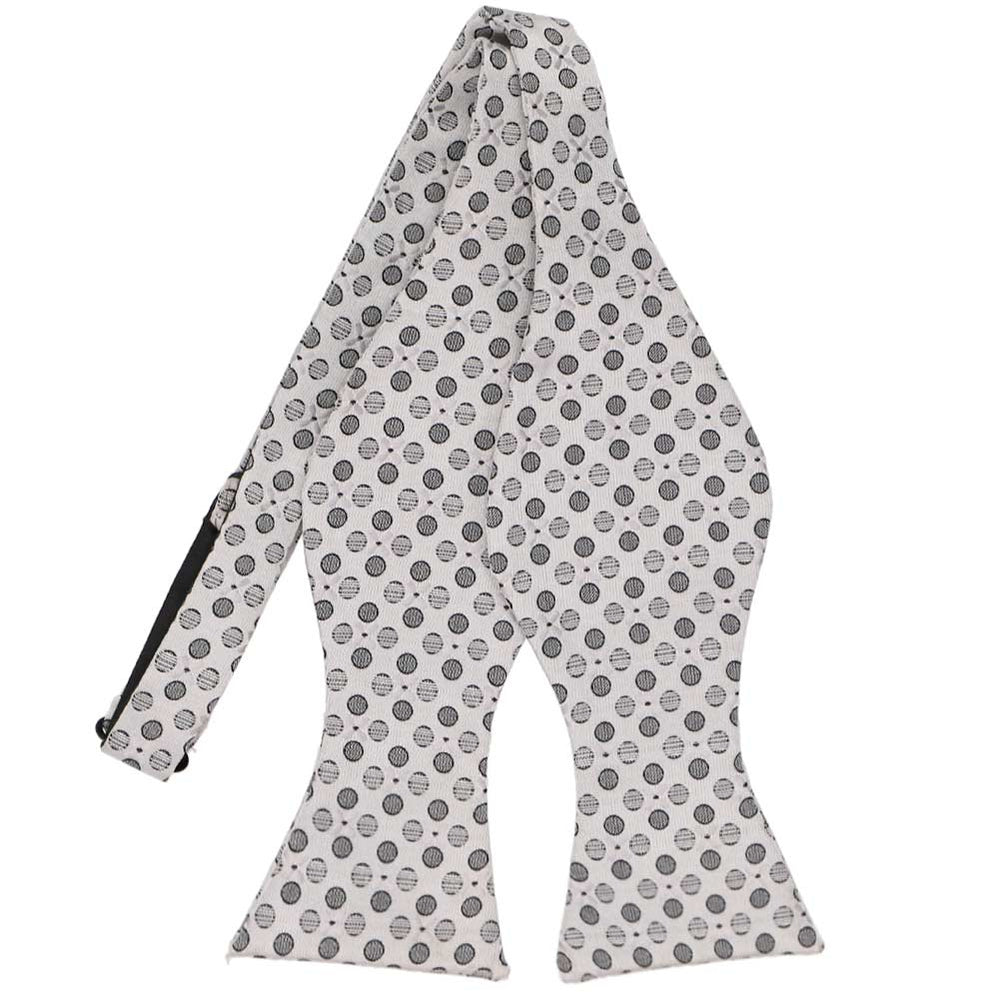 A light silver self tie bow tie, untied, with a textured dot and floral pattern