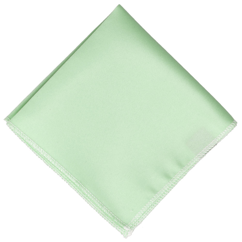 A light tea green colored pocket square, folded flat into a diamond