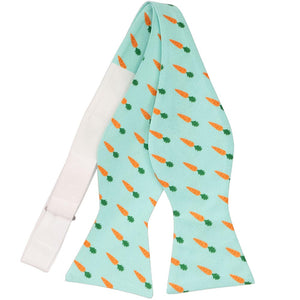 An untied self-tie bow tie with a carrot pattern on an aqua background